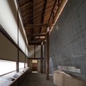 Atmospheric Light: The northern gallery of the ANDO MUSEUM by Tadao Ando (Tadao Ando Architects &amp; Associates), reveals the juxtaposition of contemporary exhibition spaces enclosed by concrete walls and placed within a reconstructed traditional Japanese house of timber, plaster, and stone. Direct sunlight, admitted from a south-facing skylight, slips over a concrete wall to illuminate the upper portion of a traditional timber-frame and plaster wall. A low linear window with translucent glazing illuminates the horizontal surface of an exhibition. Image © Yoshihiro Asada